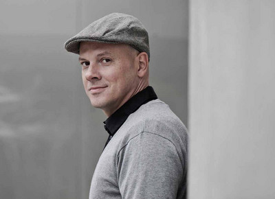 Mann mit Schirmmütze lehnt an einer Wand. 