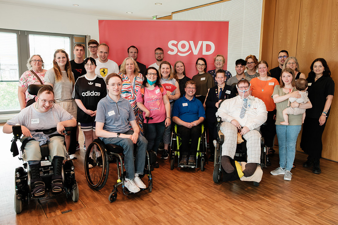 Gruppe junger Menschen vor einem roten SoVD-Aufsteller. 